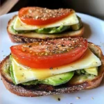 Avocado Mozzarella and Tomato Grilled Cheese sandwich on a wooden cutting board.