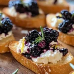Blackberry goat cheese crostini topped with fresh blackberries and herbs.