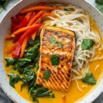 Plate of Coconut Curry Salmon served with rice noodles and garnished with herbs