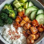 Delicious glazed chicken rice bowl with broccoli and cucumber served in a bowl