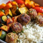 Plate of meatballs with roasted vegetables and rice, garnished and ready to serve