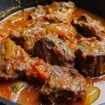 Bowl of Nigerian beef stew garnished with fresh herbs and served with rice.
