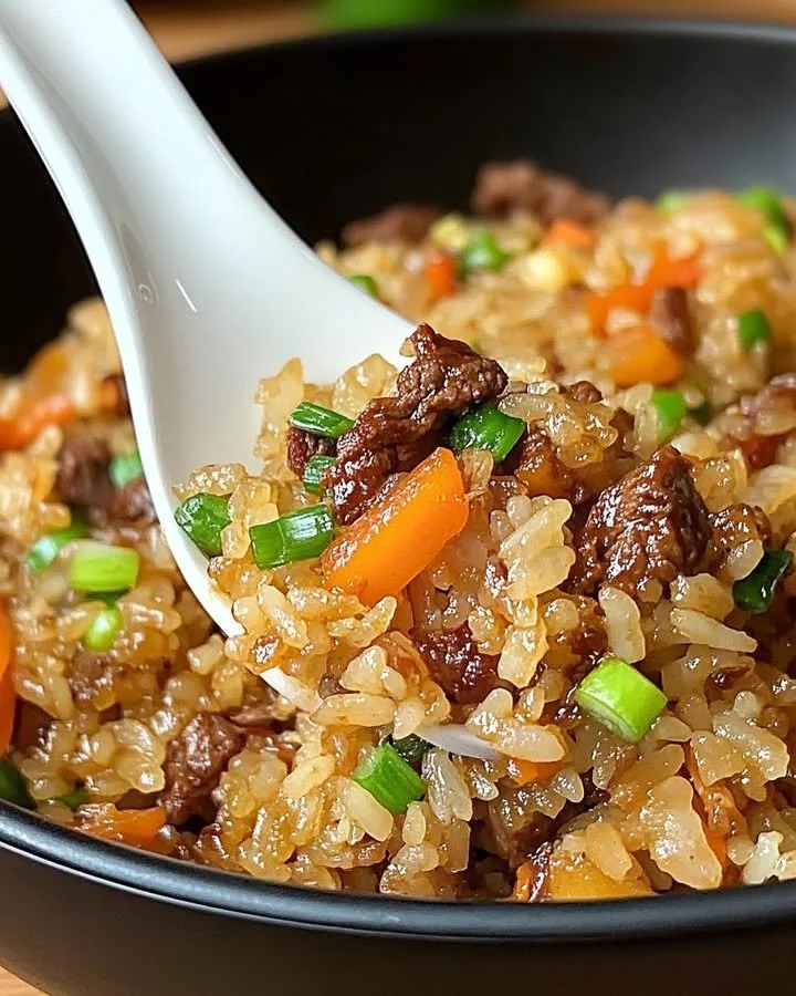 Savory onion beef fried rice served in a bowl with vegetables and beef